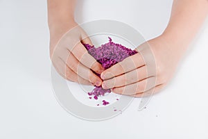 Purple kinetic sand. Child sculpts and plays with sand. Close-up view. White background