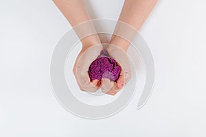 Purple kinetic sand. Child sculpts and plays with sand. Top view. White background. Space for text