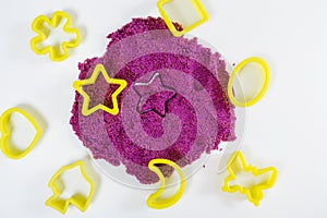 Purple kinetic sand, plastic molds for sand. Top view. White background, close-up view