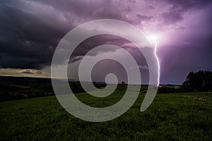 a purple lightning bolt in the night sky on a cloudy day