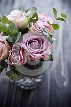 Purple, mauve color fresh summer roses in vase with black tablet