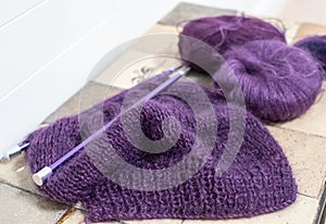 Purple mohair and alpaca yarn hand knitted sweater with stitches including stocking stitch and rib, on straight knitting needles.