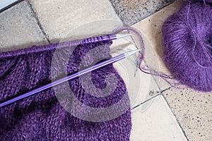 Purple mohair and alpaca yarn hand knitted sweater with stitches including stocking stitch and rib, on straight knitting needles.