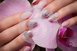 Purple neat manicure on female hands on flowers background. Nail design