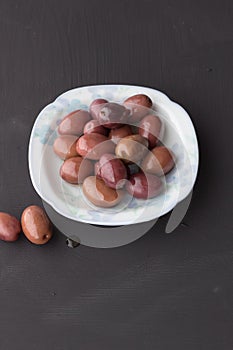 Purple olives in small white bowl with two on black chalk board