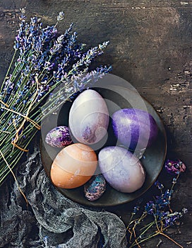 Purple painted Easter eggs with lavender on dark rustic background
