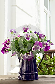 Purple pansies in blue jug