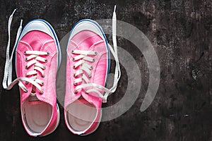 purple-pink-lilac sneakers with untied laces on a dark concrete background. Copy space. View from above