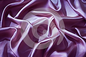 Purple pink silk satin. Shiny fabric. Wavy folds. Beautiful lilac background with space for design.