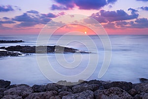 Purple and pink sunset over ocean shore