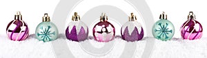 Purple, pink & turquoise Christmas baubles in snow isolated