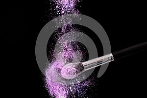 Purple powder explosion dust and make up brush on black background