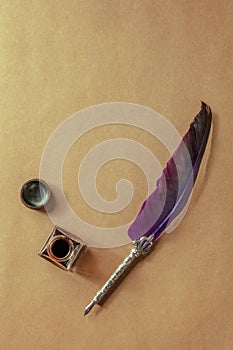 Purple quill pen with a vintage inkwell, shot from the top