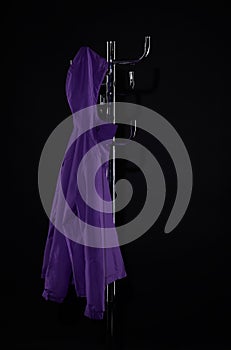 purple raincoat hanging on coat rack on black