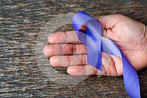 Purple ribbon for the awareness about the unacceptability of the violence against women on dark gray rustic wooden surface. Top