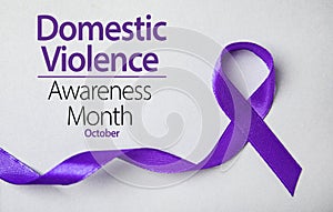 Purple ribbon on background, top view. Symbol of Domestic Violence Awareness