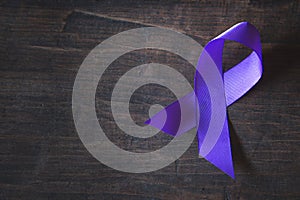 Purple ribbon on black wood background,  Pancreatic cancer, Epilepsy awareness, domestic violence awareness,  world cancer day