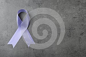 Purple ribbon on grey stone background, top view. Domestic violence awareness