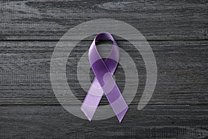 Purple ribbon on grey wooden background. Domestic violence awareness