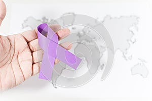 Purple ribbon on a person's hand - awareness of violence against women concept