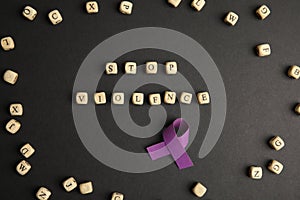 Purple ribbon and phrase STOP VIOLENCE made of cubes on black background, flat lay