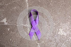 Purple ribbon on stone background. Domestic violence awareness