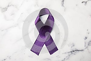 Purple ribbon on white marble background. Domestic violence awareness