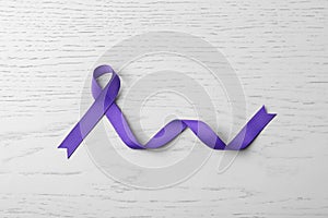 Purple ribbon on white wooden background. Domestic violence awareness