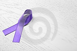 Purple ribbon on white wooden background. Domestic violence awareness