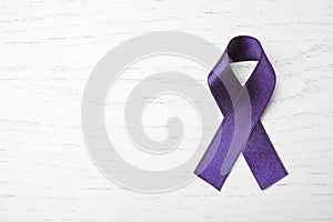 Purple ribbon on white wooden background, top view. Domestic violence awareness