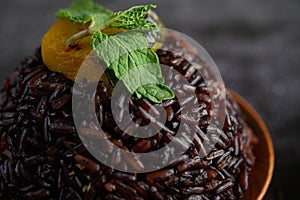 Purple rice berries cooked in a wooden dish with mint leaves and pumpkin