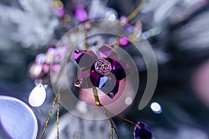 Purple shiny crystal flower Christmas tree decoration bauble on a blue bokeh background