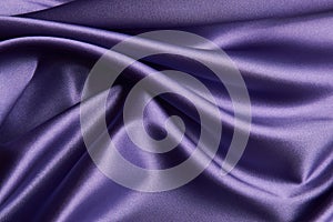 Purple silk fabric background, close-up. Smooth violet satin cloth texture