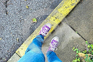 Purple sneakers on the sidewalk curb