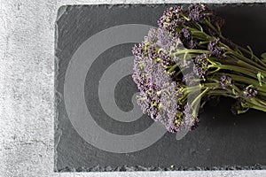 Purple sprouting broccoli on a slate chopping board.