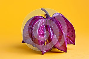 A purple star fruit with its cut off side facing the camera, on an isolated yellow background. Ai generated