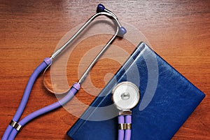 Purple stethoscope and notebook on a wooden background