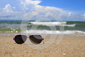 Purple Sunglasses on sand at Beach.