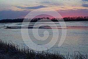 Purple sunrise along the Platte river in Nebraska with the silhouette of distant birds in flight