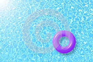 Purple swimming pool ring float in blue water and sun bright. photo