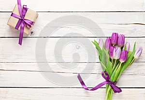 Purple tulips and gift box over wooden table