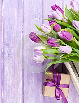 Purple tulips and gift box over wooden table