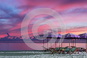 Purple umbrella and green chairs in morning beach, sunrise shot