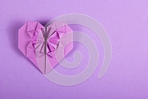 Purple Valentine origami on a lilac background. Heart of paper. Surprise on Valentine`s Day.