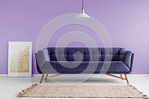 Purple, velvet sofa and a beige rug in a pastel lavender living room interior with a poster mock-up. Real photo.