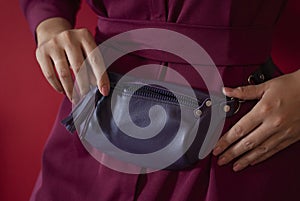 Purple waist bag made from natural leather close-up view on the unrecognizable woman on the green background