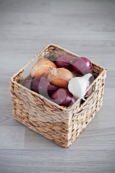 Purple and white onions in squar, wicker box on the wooden background