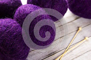 The purple yarn and knitting needles on the table