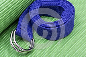 Purple Yoga Strap on Green Yoga Mat. Exercises for beginners