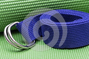 Purple Yoga Strap on Green Yoga Mat. Exercises for beginners